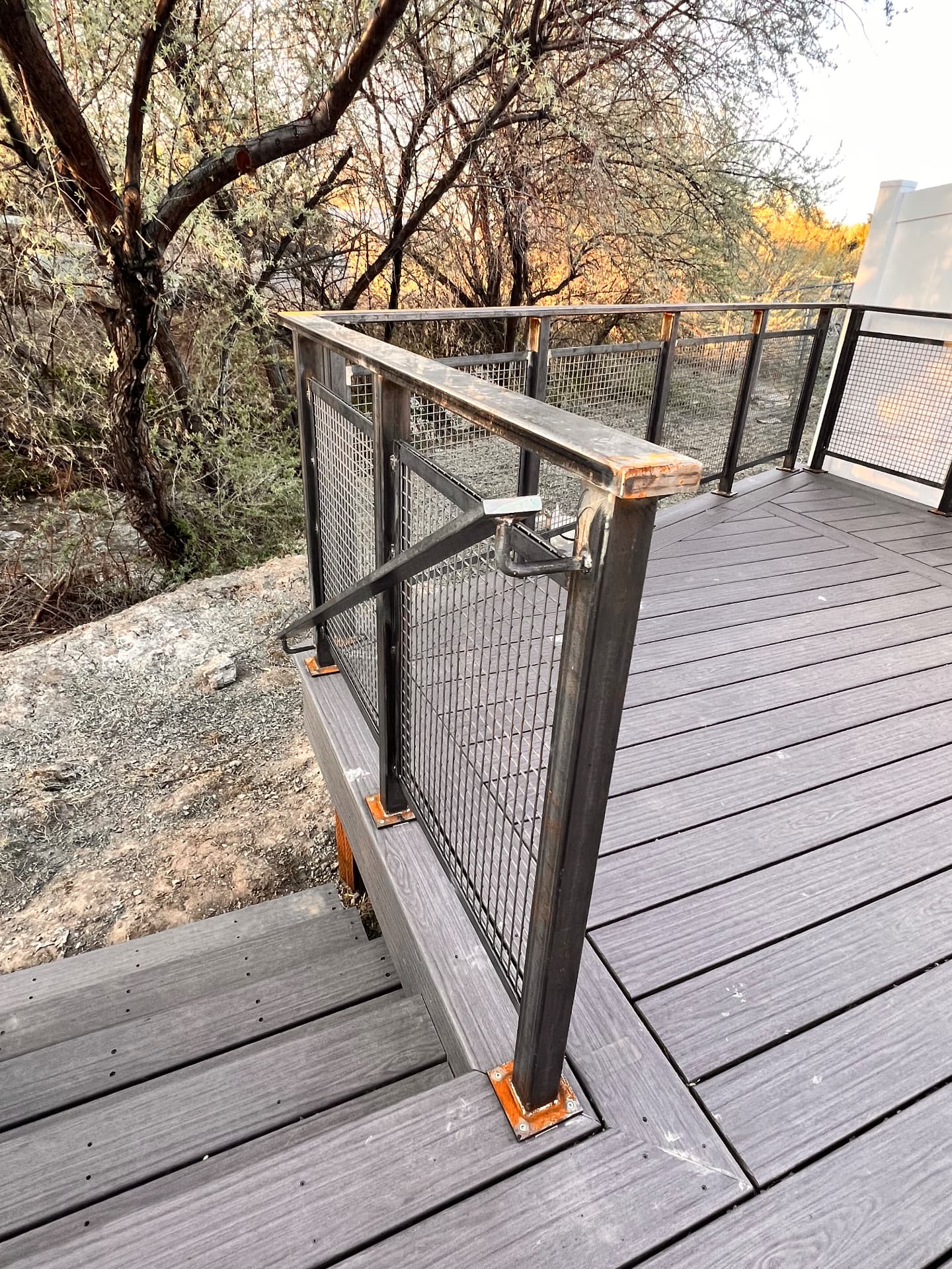 Custom steel mesh deck railing installed along a composite deck overlooking trees