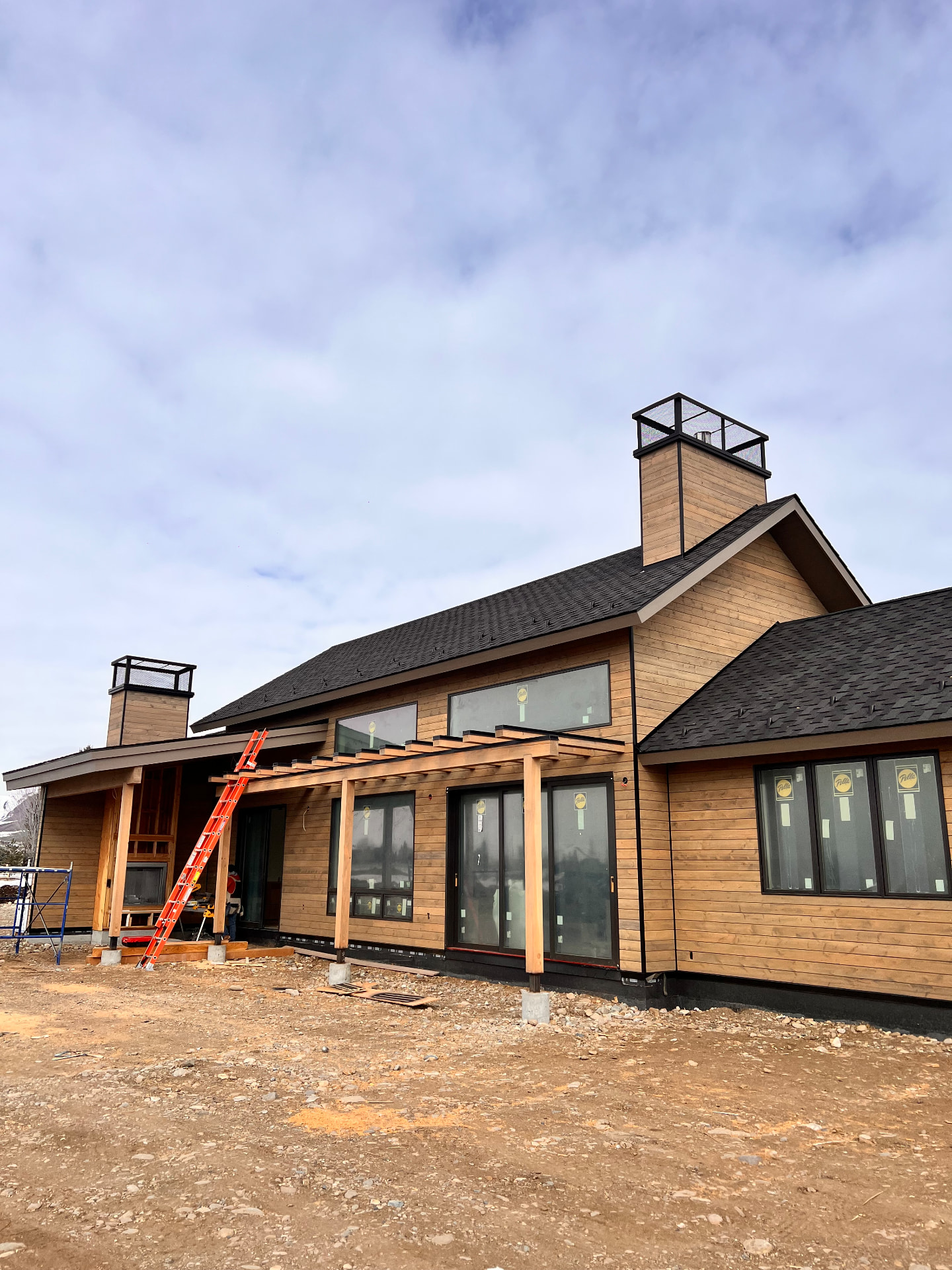 Custom black steel chimney cap installed on a large mountain home under construction