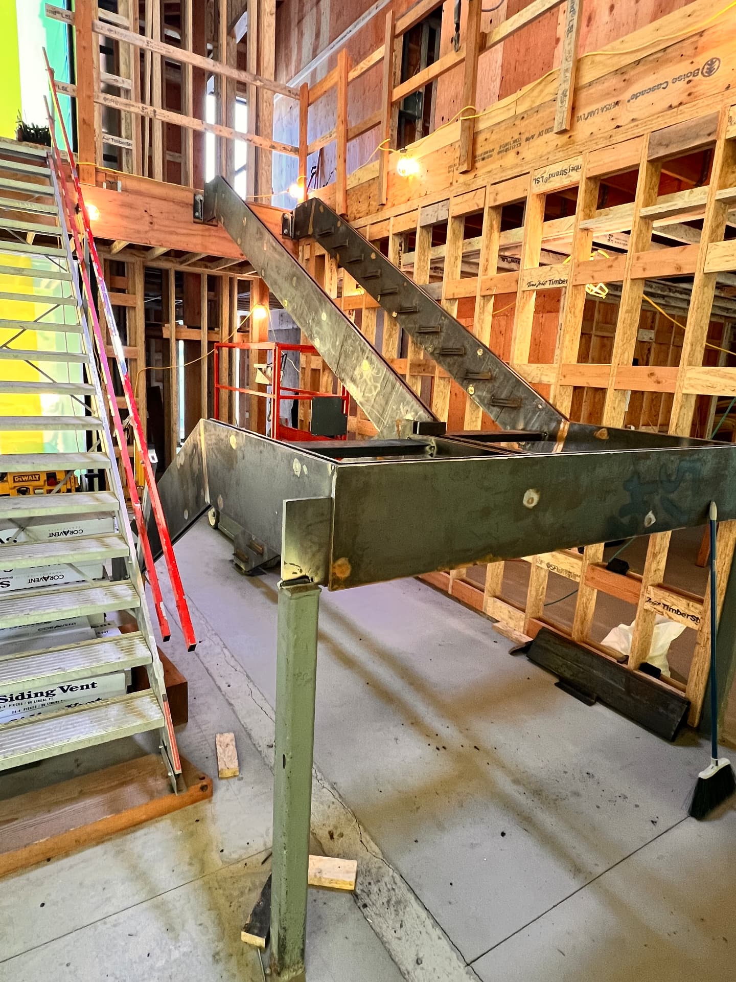 Welded steel landing and beam assembly with a support column inside a framed residential interior