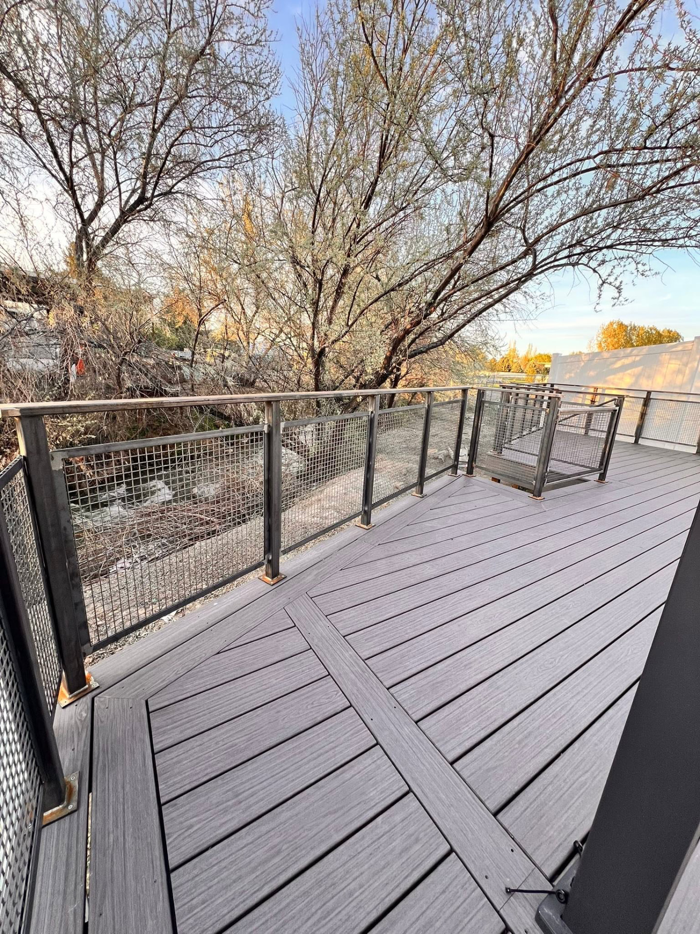 Composite deck with welded steel mesh panel railings and angled deck boards
