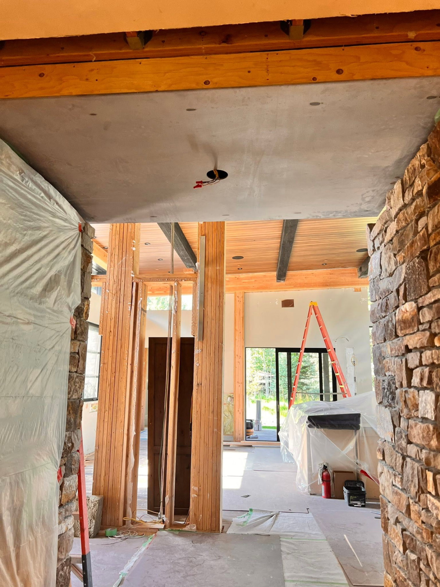 Exposed wood framing and stone columns inside a home during a structural remodel
