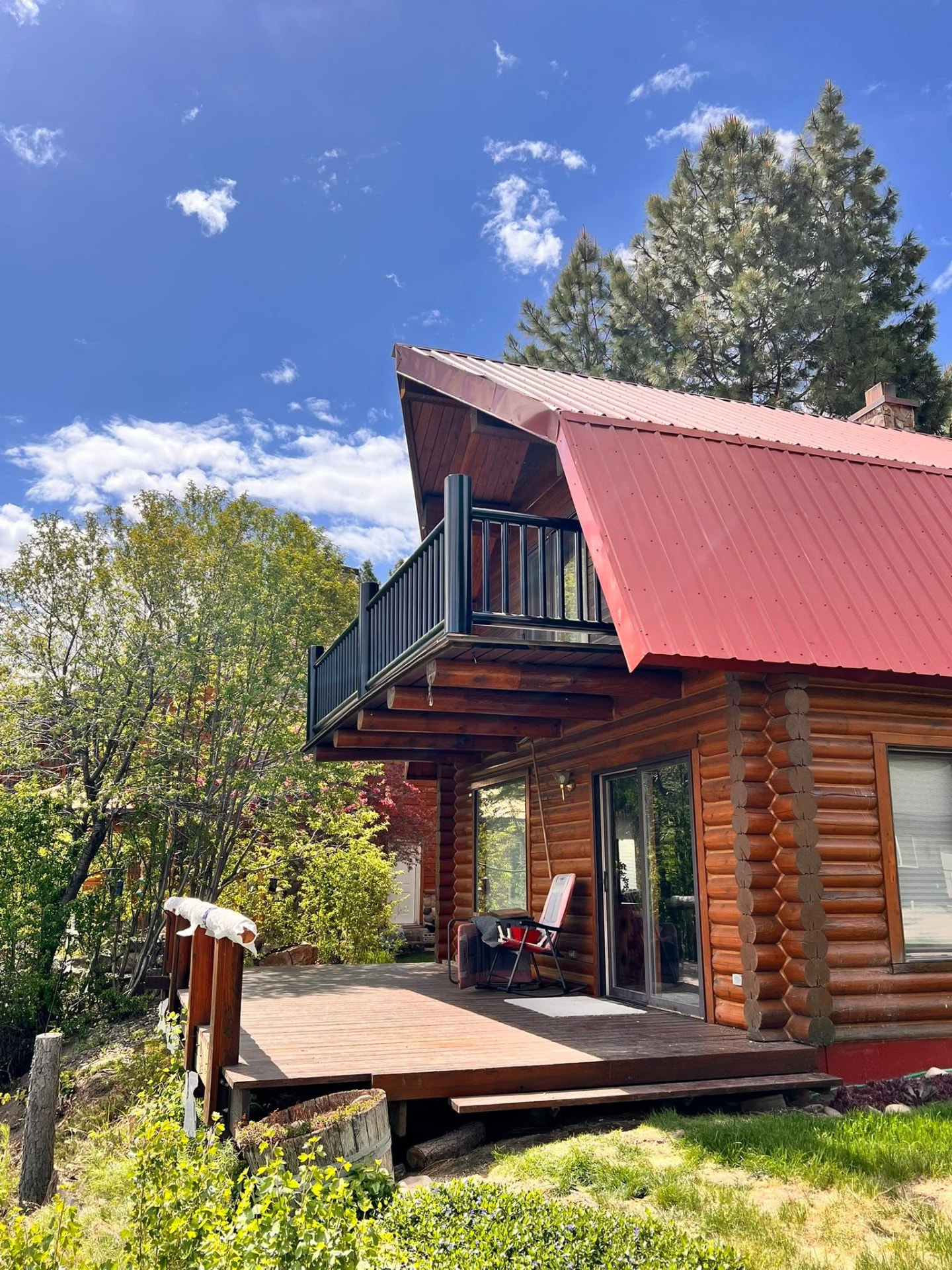 Log cabin balcony with a custom black steel railing under a red metal roof