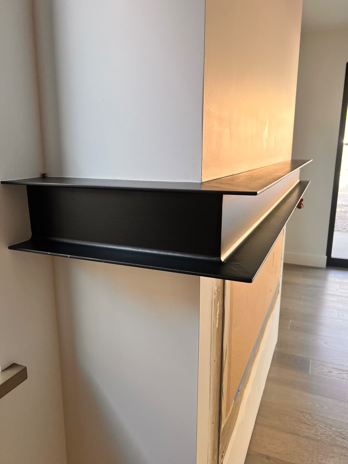 Custom black steel fireplace mantle wrapping a white chimney breast in a modern home
