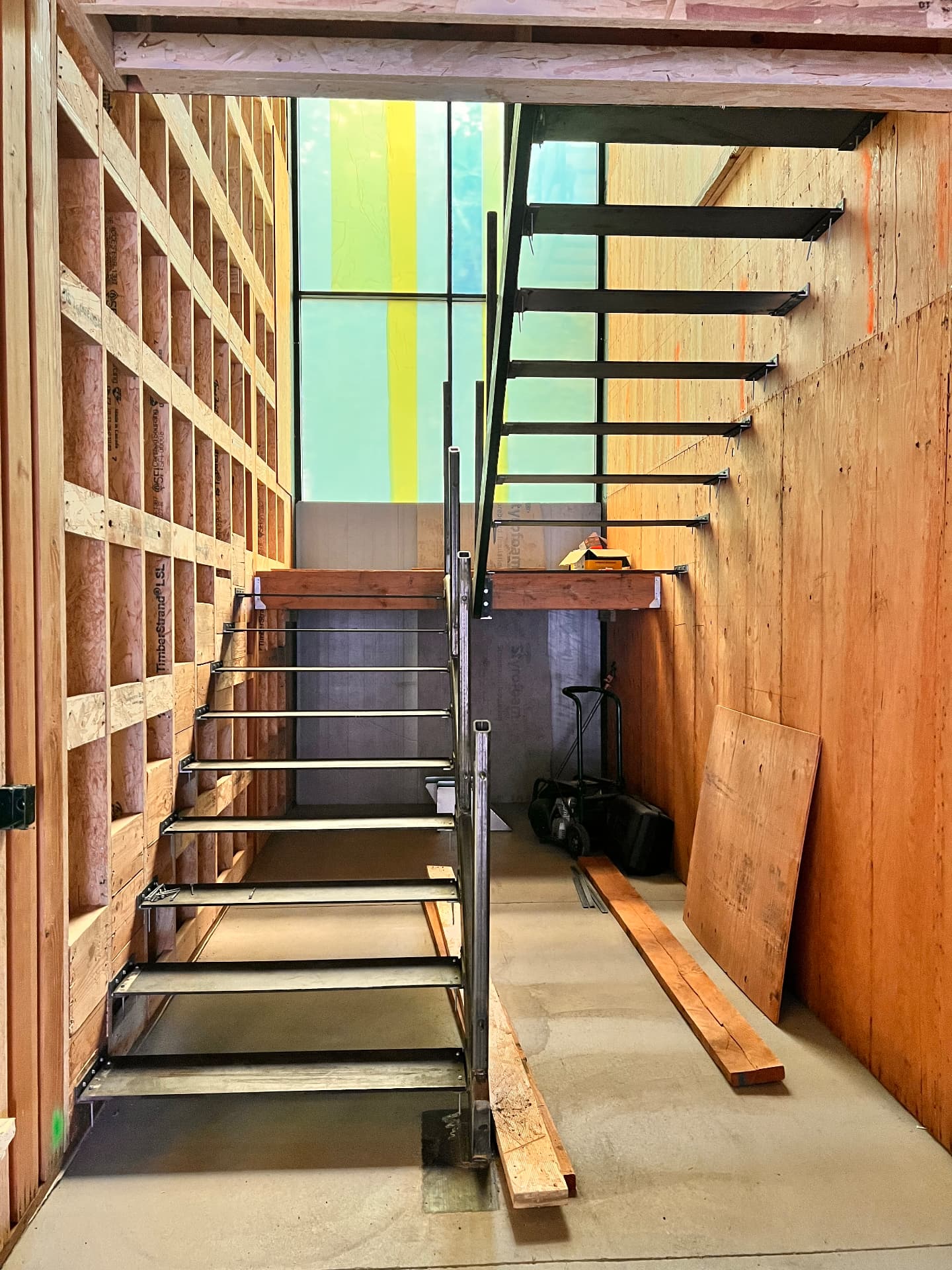 Steel staircase with metal stair pans and handrail posts under construction, viewed from the side