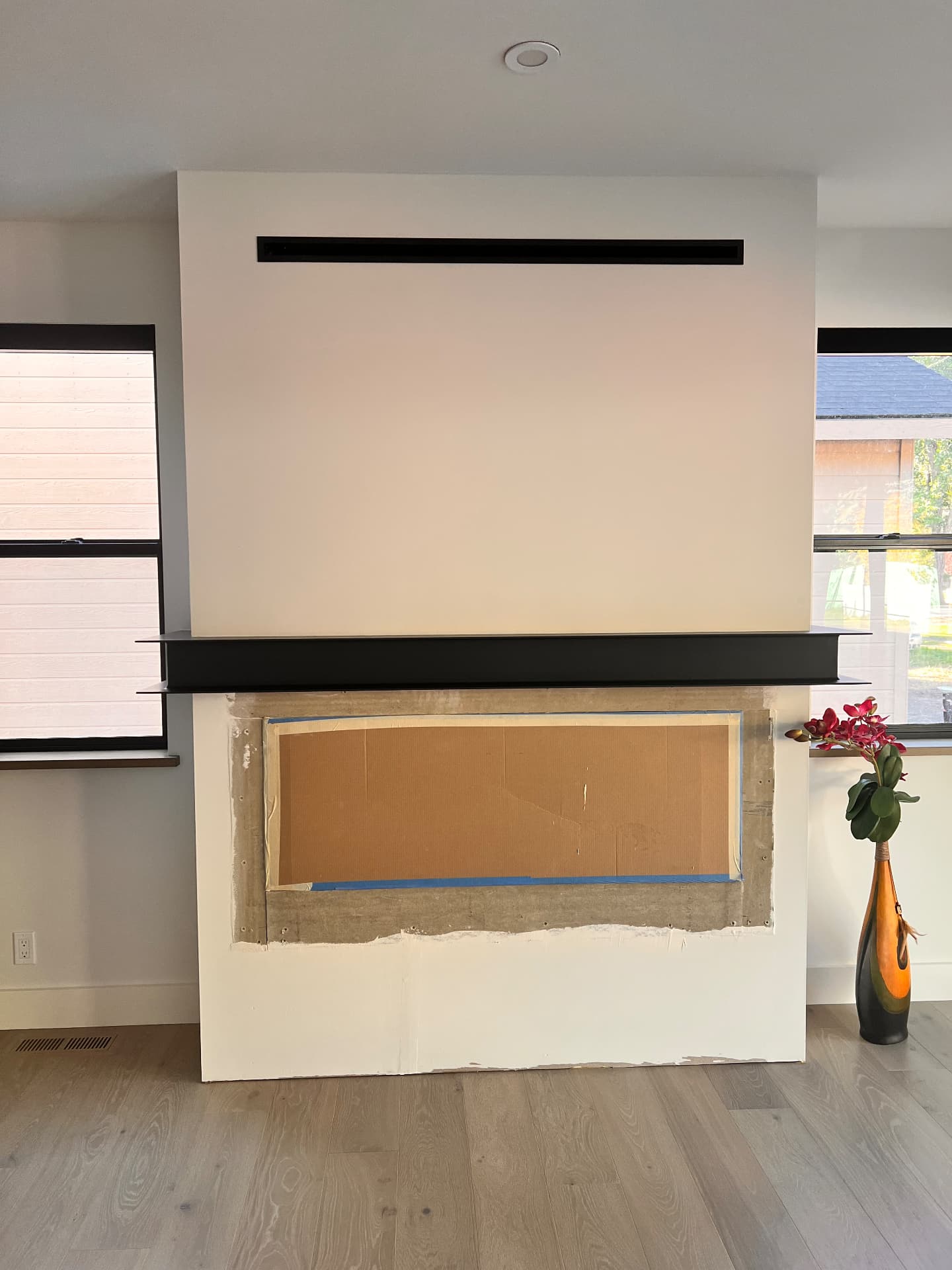 Custom black steel fireplace mantle and recessed screen housing in a modern interior